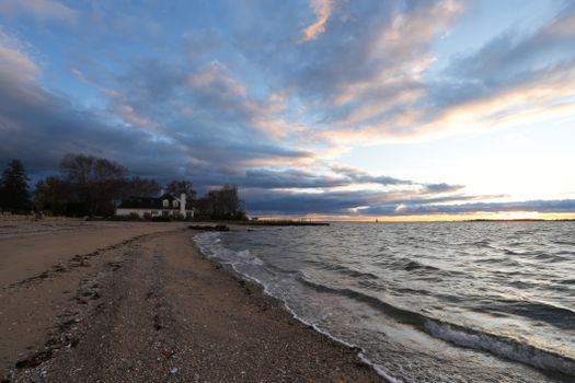 Serene beach at sunset with lush clouds and gentle waves.