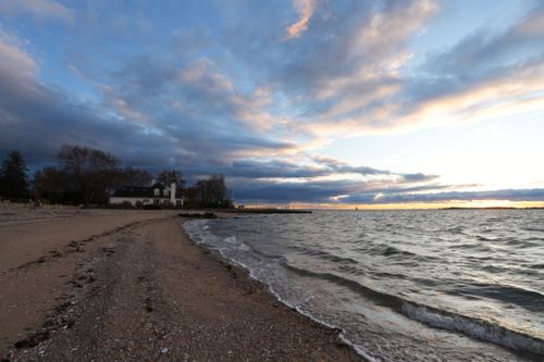Free Serene beach at sunset with lush clouds and gentle waves. Stock Photo