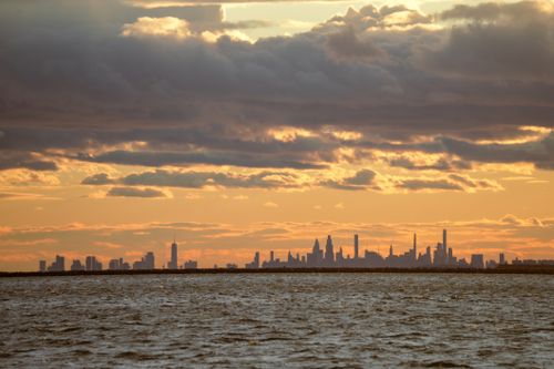 Free New York City skyline silhouetted against a vibrant sunset seen from the water. Stock Photo