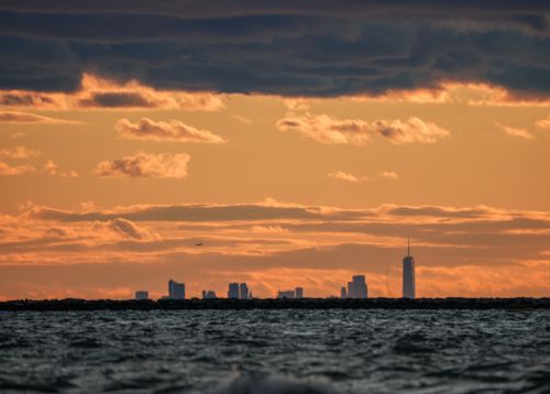 Free Stunning city skyline silhouette beneath a vivid sunset sky over the water. Stock Photo