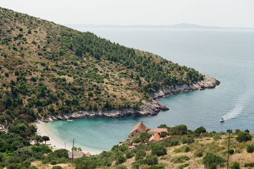 Free A picturesque coastal cove with a lush hillside and clear blue waters, ideal for travel enthusiasts. Stock Photo