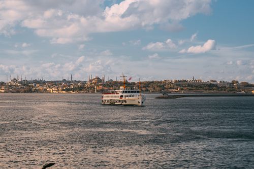 Free Scenic view of a ferry on the Bosphorus with the historic Istanbul skyline under a partly cloudy sky. Stock Photo