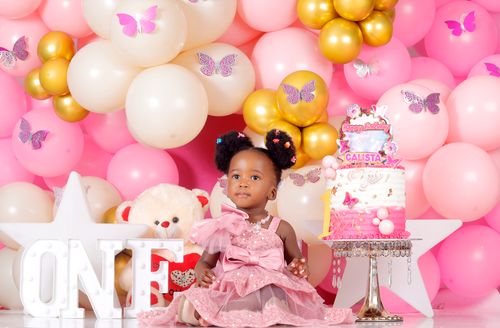 Free A little girl celebrates her first birthday with a pink-themed party and a decorated cake. Stock Photo