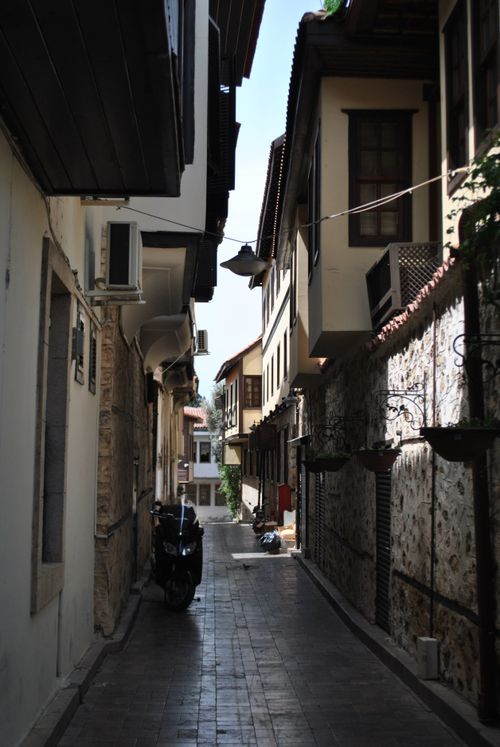 Free A charming cobblestone alley between historic buildings with a scooter parked, capturing a classic European city vibe. Stock Photo