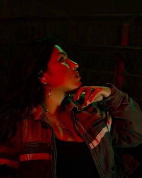 Striking portrait featuring colorful lighting effects and a contemplative pose.