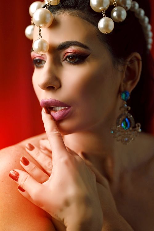 Free Close-up of a woman adorned with pearl headpiece, showcasing elegance and allure against a red backdrop. Stock Photo