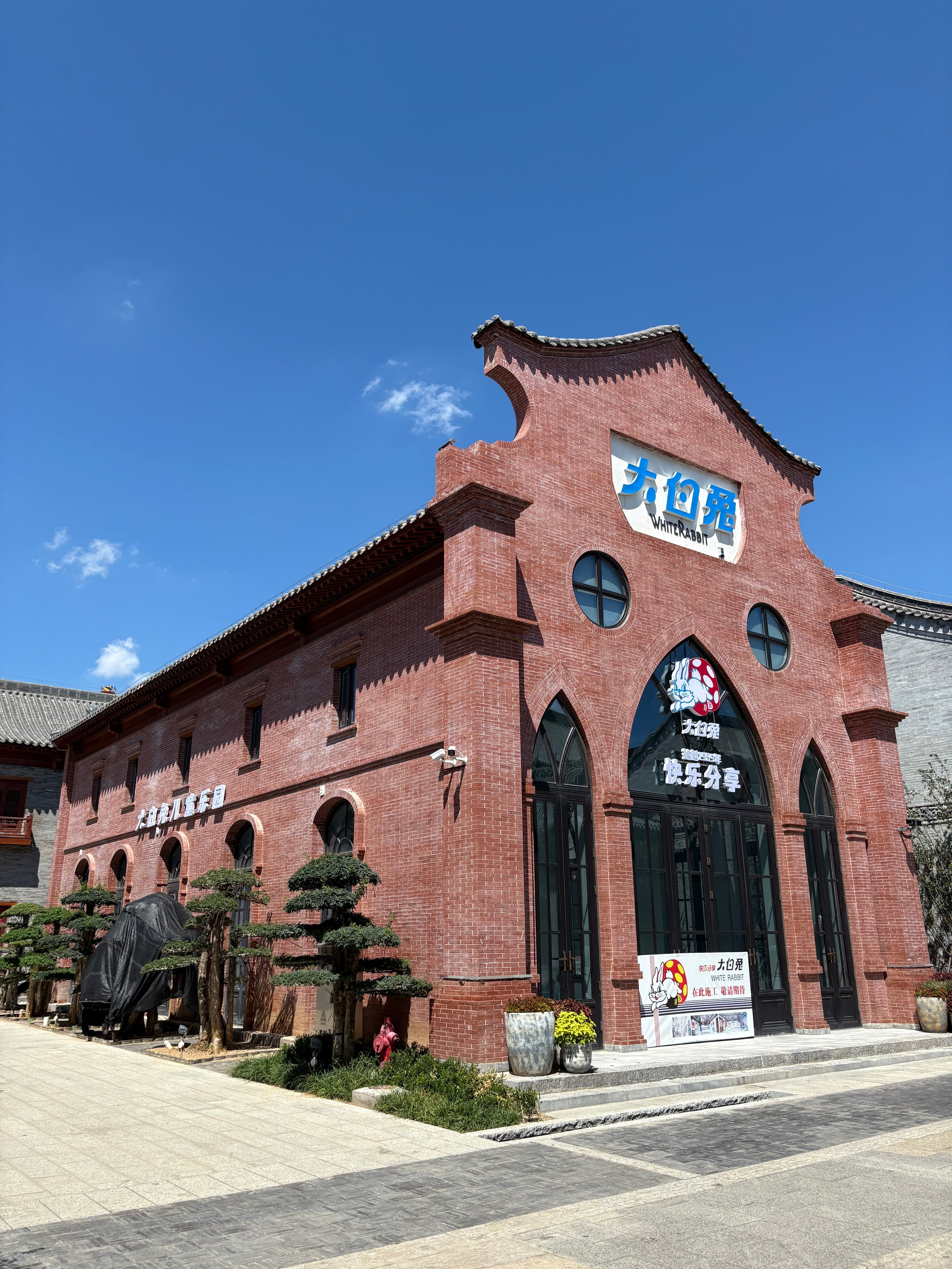 Historic red brick building with traditional Chinese architectural elements against a clear blue sky.