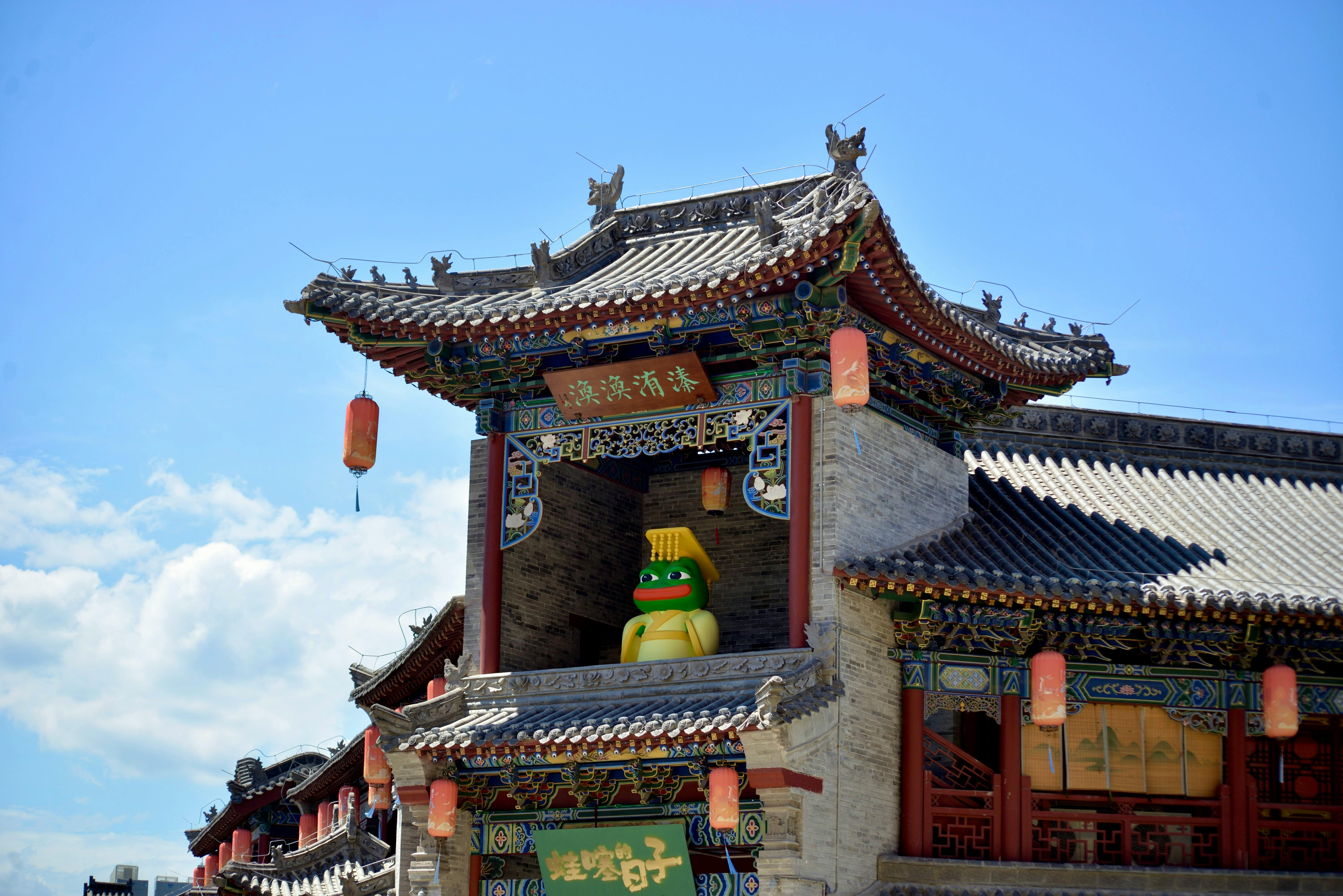 Colorful traditional Chinese building with ornate roof and red lanterns under a clear blue sky.