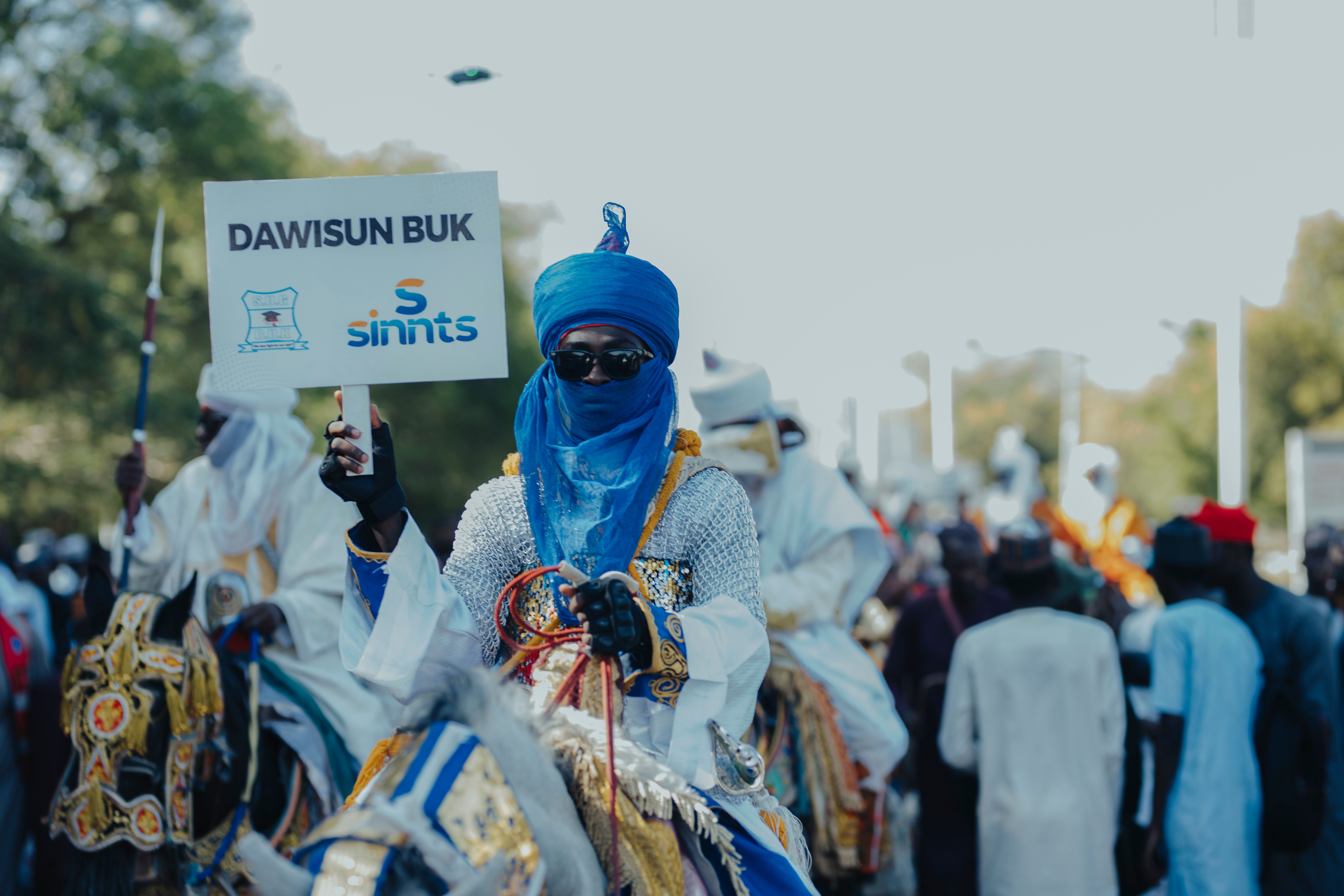 Colorful parade with traditionally dressed riders and cultural banners, showcasing rich African heritage.
