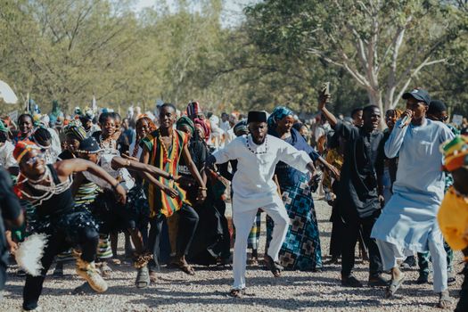 A lively outdoor gathering of African people engaging in traditional cultural dance.