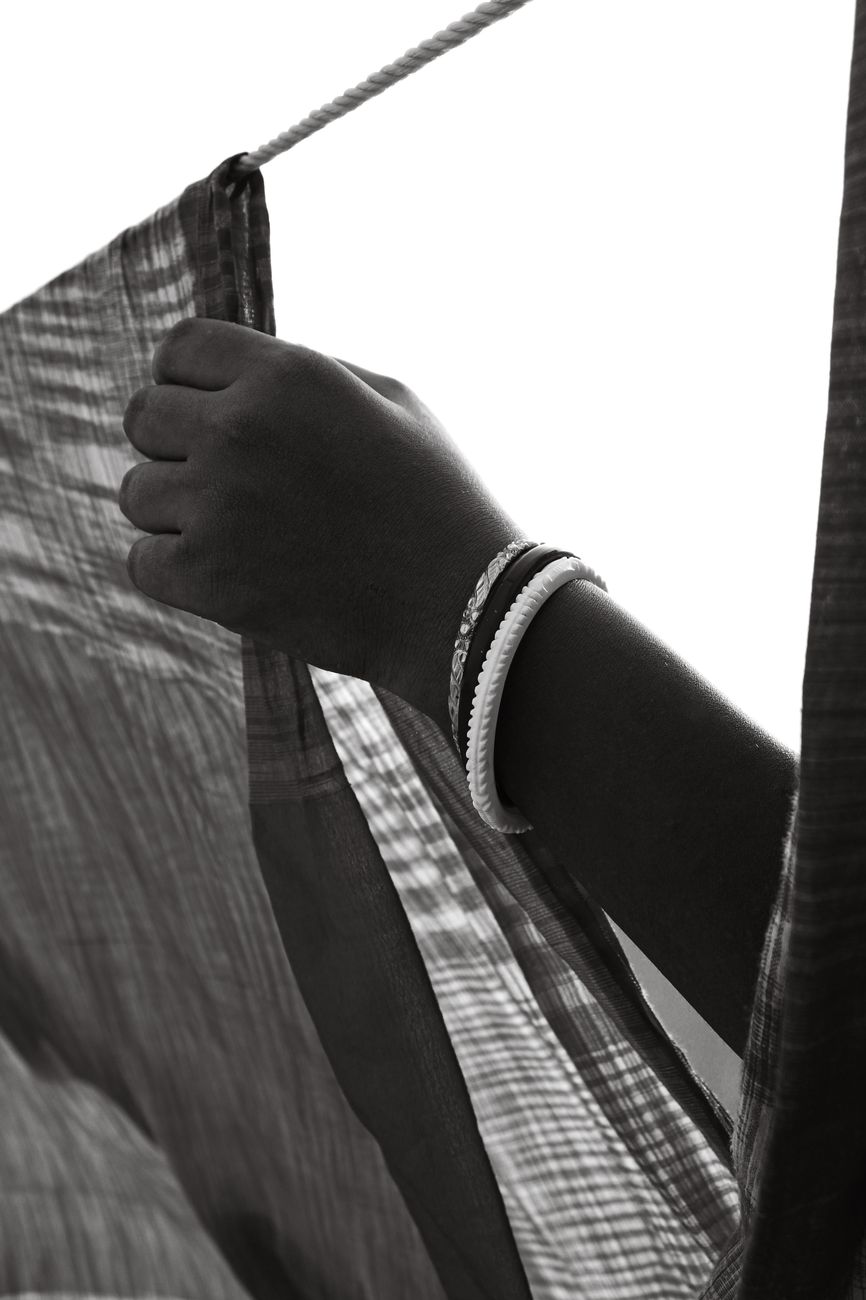 Black and white photo of a hand holding fabric, adorned with bracelets, exuding a vintage aesthetic.