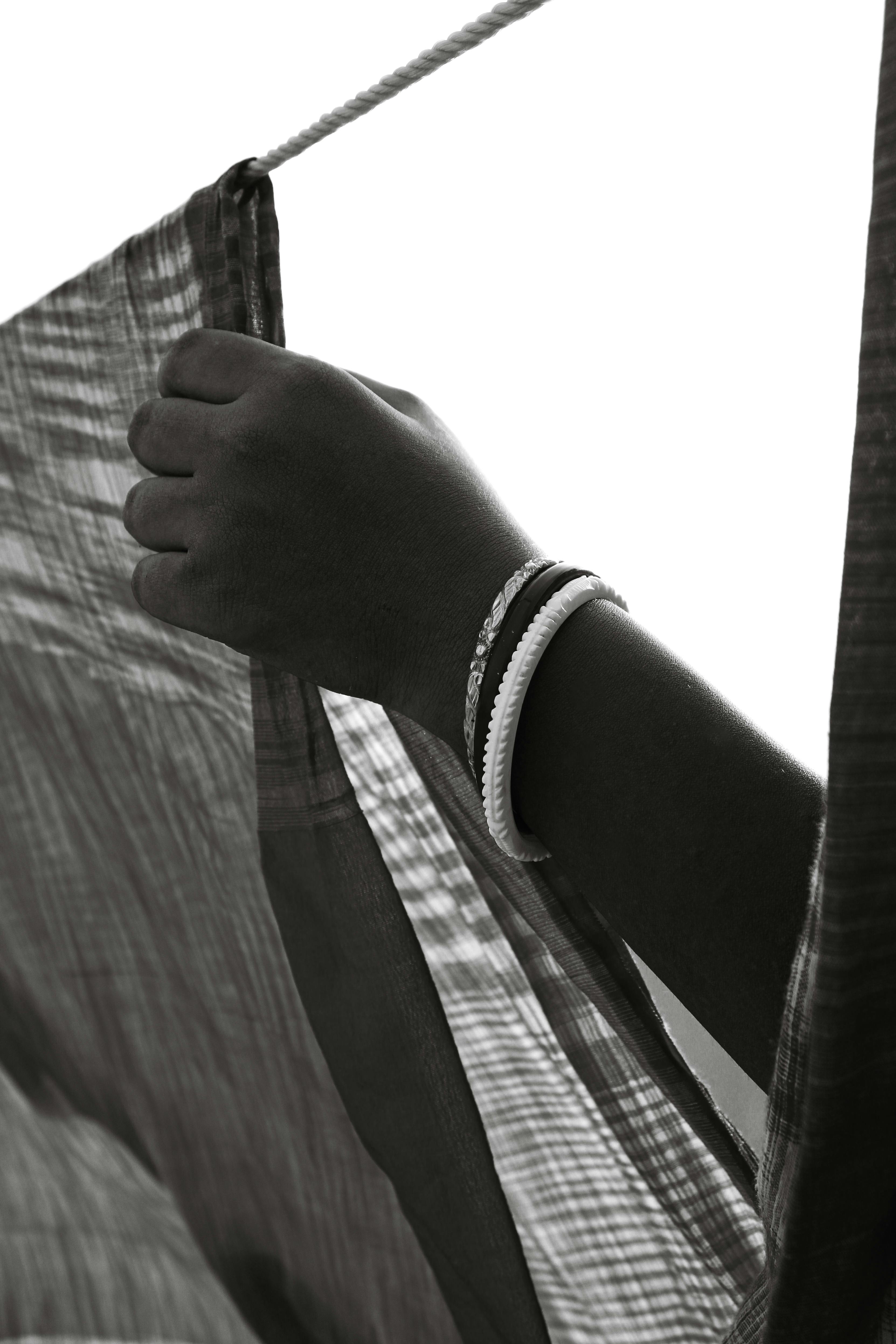 Gratis Fotografía en blanco y negro de una mano sosteniendo una tela, adornada con pulseras, que exhala una estética vintage. Foto de stock