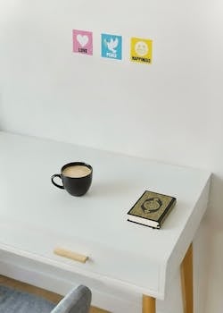A serene workspace featuring a Quran, coffee cup, and motivational posters, promoting love, peace, and happiness.