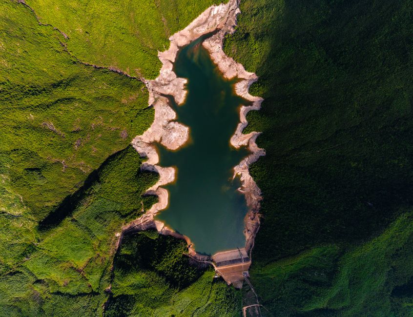 Spectacular aerial shot of a reservoir with rugged shores enveloped by verdant greenery.