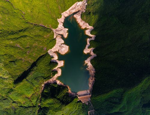 Free Spectacular aerial shot of a reservoir with rugged shores enveloped by verdant greenery. Stock Photo