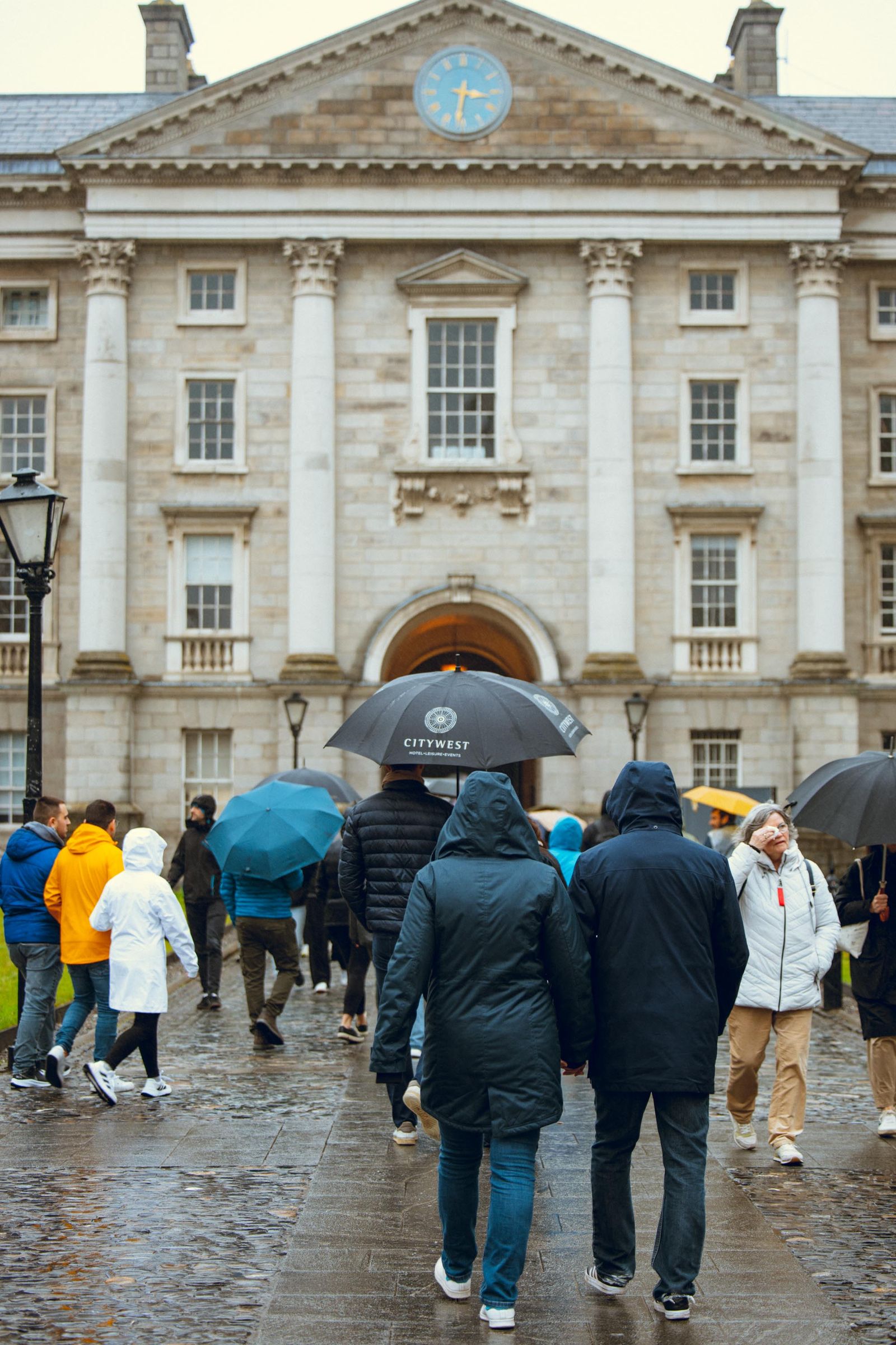 Visitors arriving at Trinity College Dublin with umbrellas