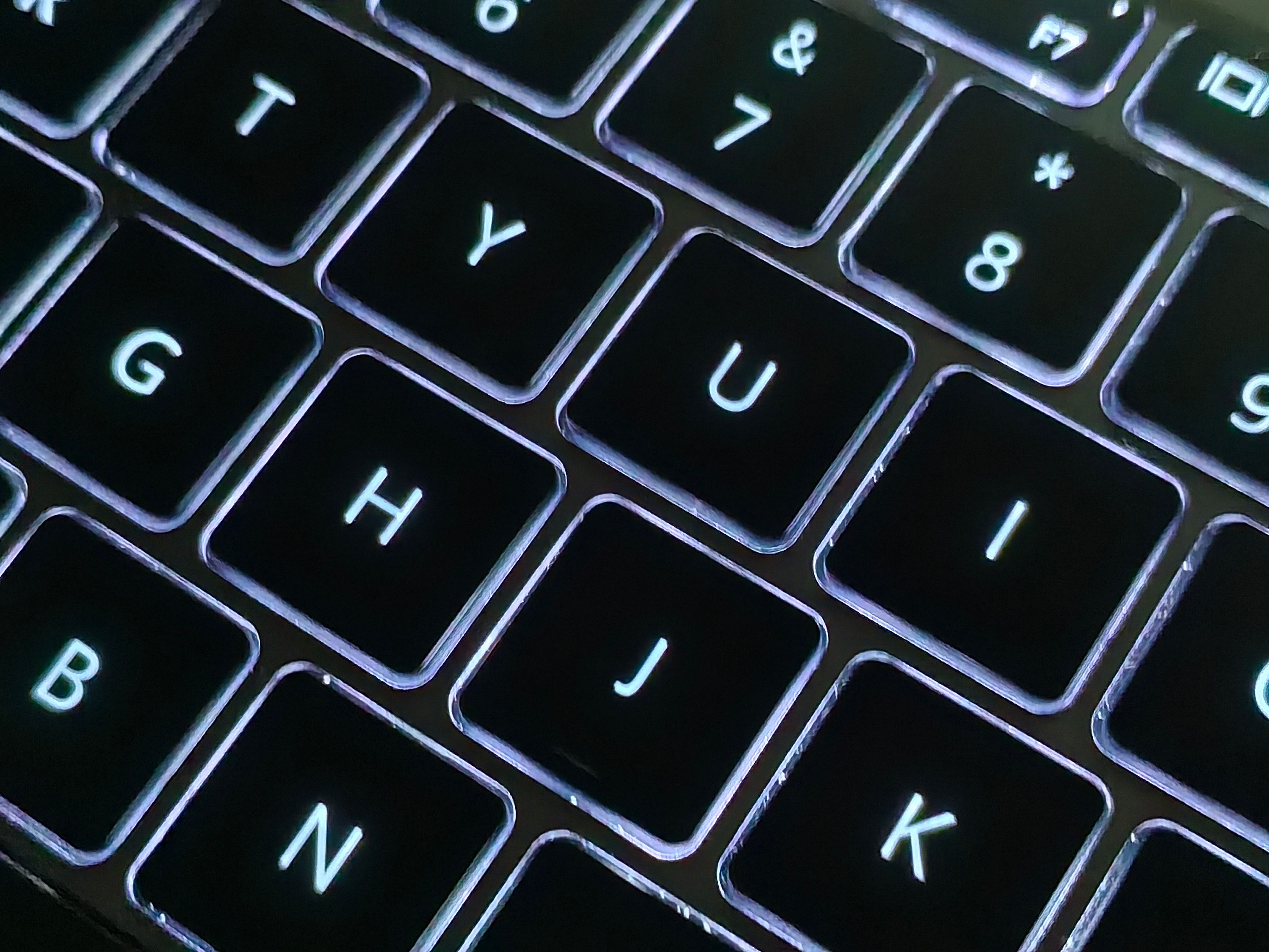 A detailed close-up photo of a backlit laptop keyboard with glowing keys, showcasing modern technology.