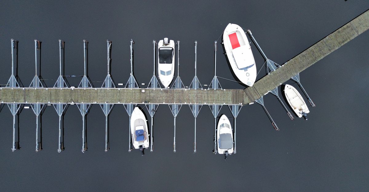 Aerial shot of a marina pier with boats docked, showcasing symmetry and structure.