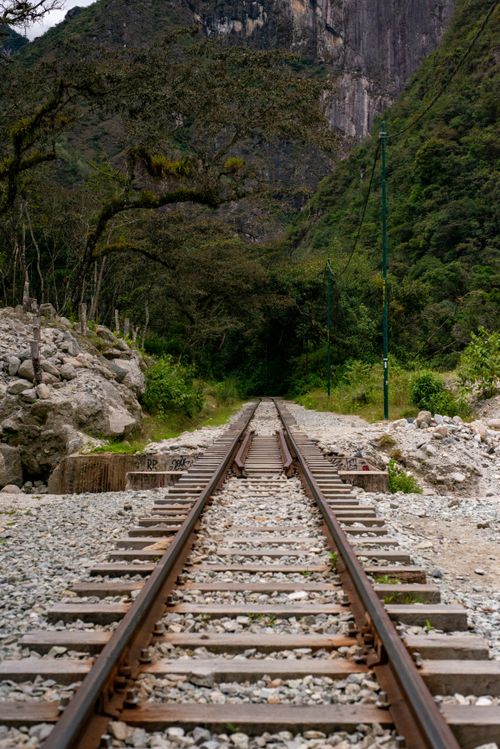 Free A scenic view of railway tracks disappearing into lush forest and mountains, offering a sense of adventure. Stock Photo