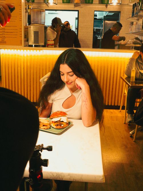 Free Woman seated in a stylish cafe with a gourmet burger and fries. Stock Photo