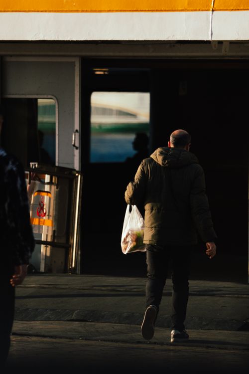 Free Adult male entering a building with a plastic shopping bag during the day in an urban setting. Stock Photo