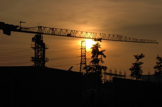 Silhouette of a construction crane with a sunset backdrop, highlighting urban development.