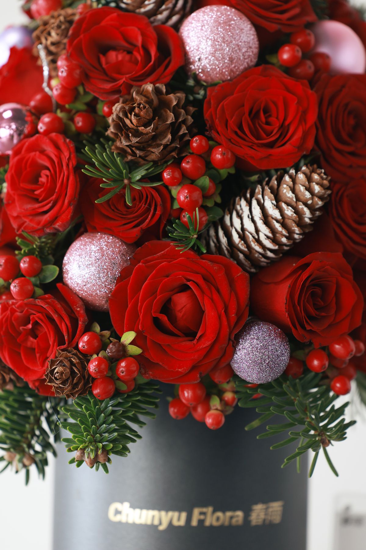 Festive bouquet combining red roses, pinecones, and berries for Christmas centerpiece ideas