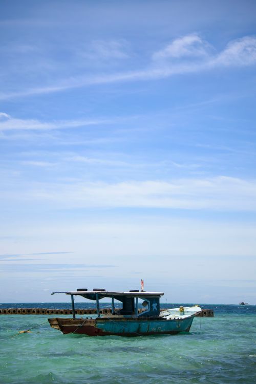 Free A serene scene of a traditional fishing boat floating on the calm sea near Jakarta, Indonesia. Stock Photo