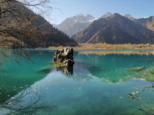 Free Idyllic mountain lake in autumn with crystal clear water and snow-capped mountains. Stock Photo