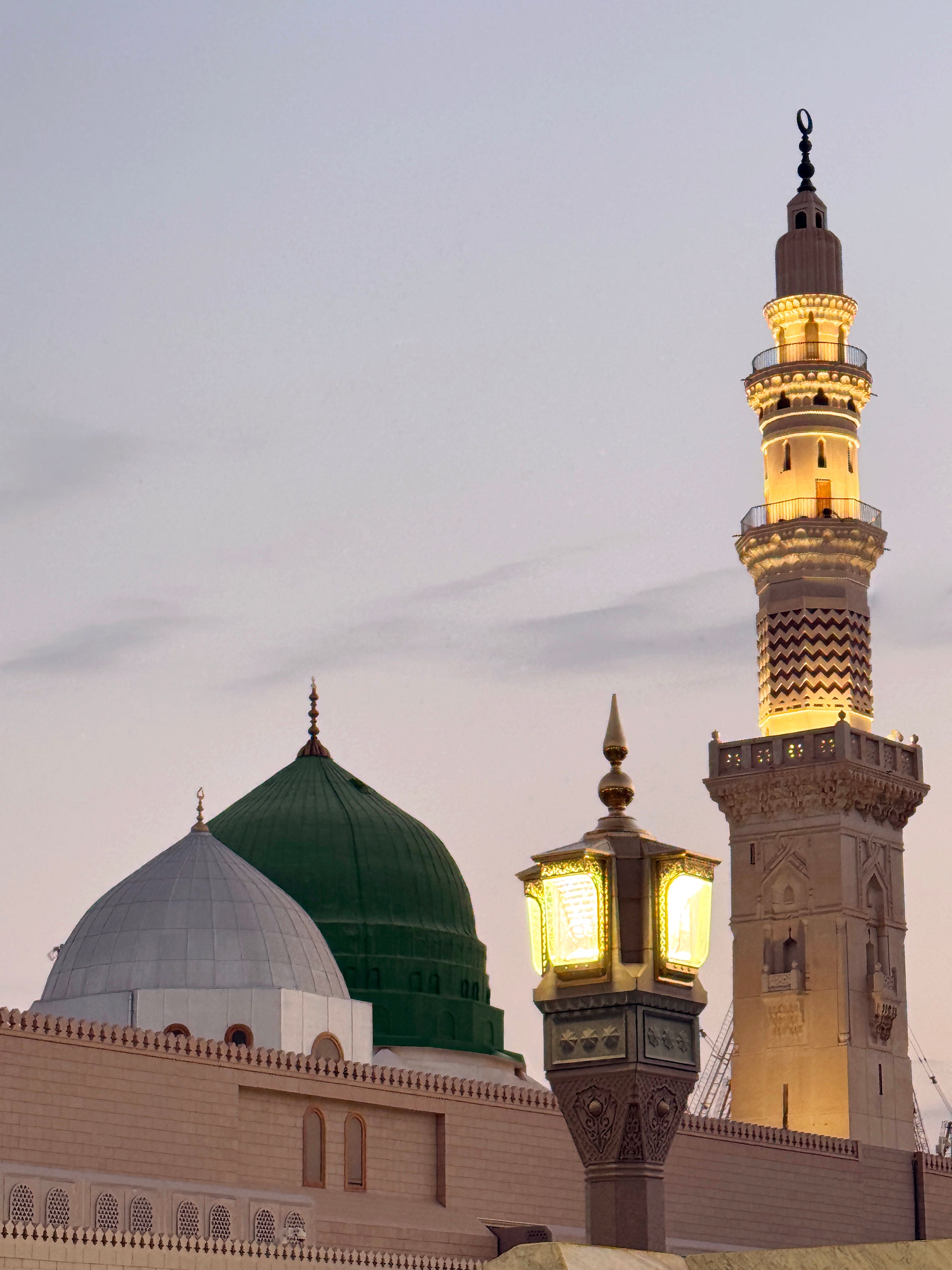 Beautiful view of Al-Masjid an-Nabawi's minaret and domes in Medina, Saudi Arabia, during twilight, capturing its serene atmosphere.