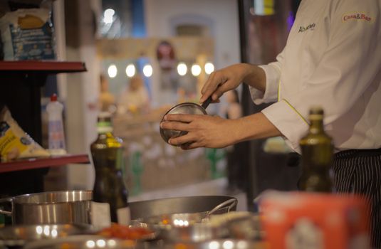 A chef carefully preparing a meal in a warmly lit, cozy restaurant kitchen setting.