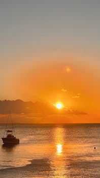 Beautiful sunset with boat silhouette on tranquil ocean waters.