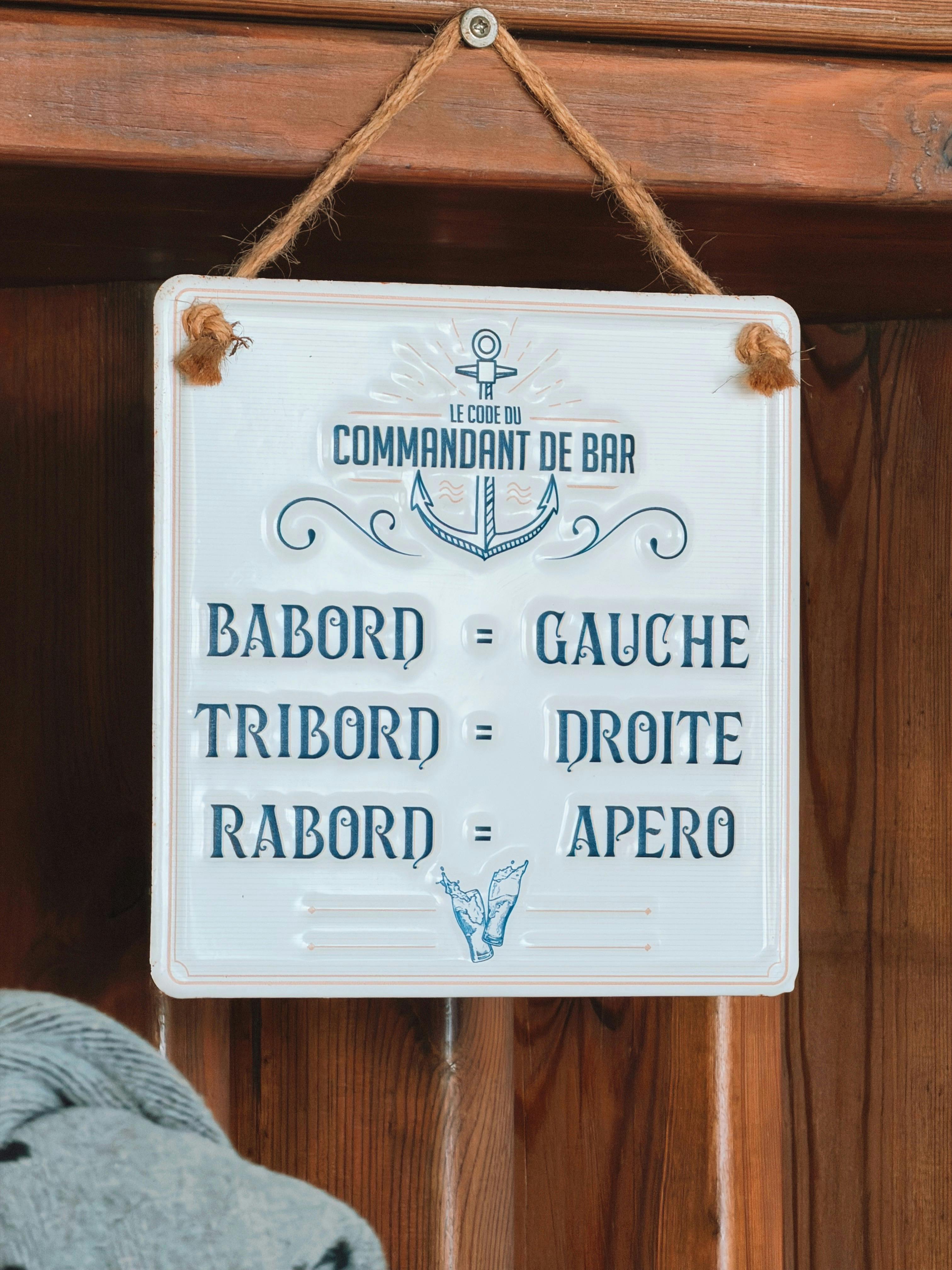 Rustic nautical-themed sign with French phrases for left, right, aperitif.