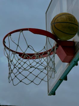 Close-up of basketball about to enter the hoop against a cloudy sky. Captured in Veracruz, Mexico.
