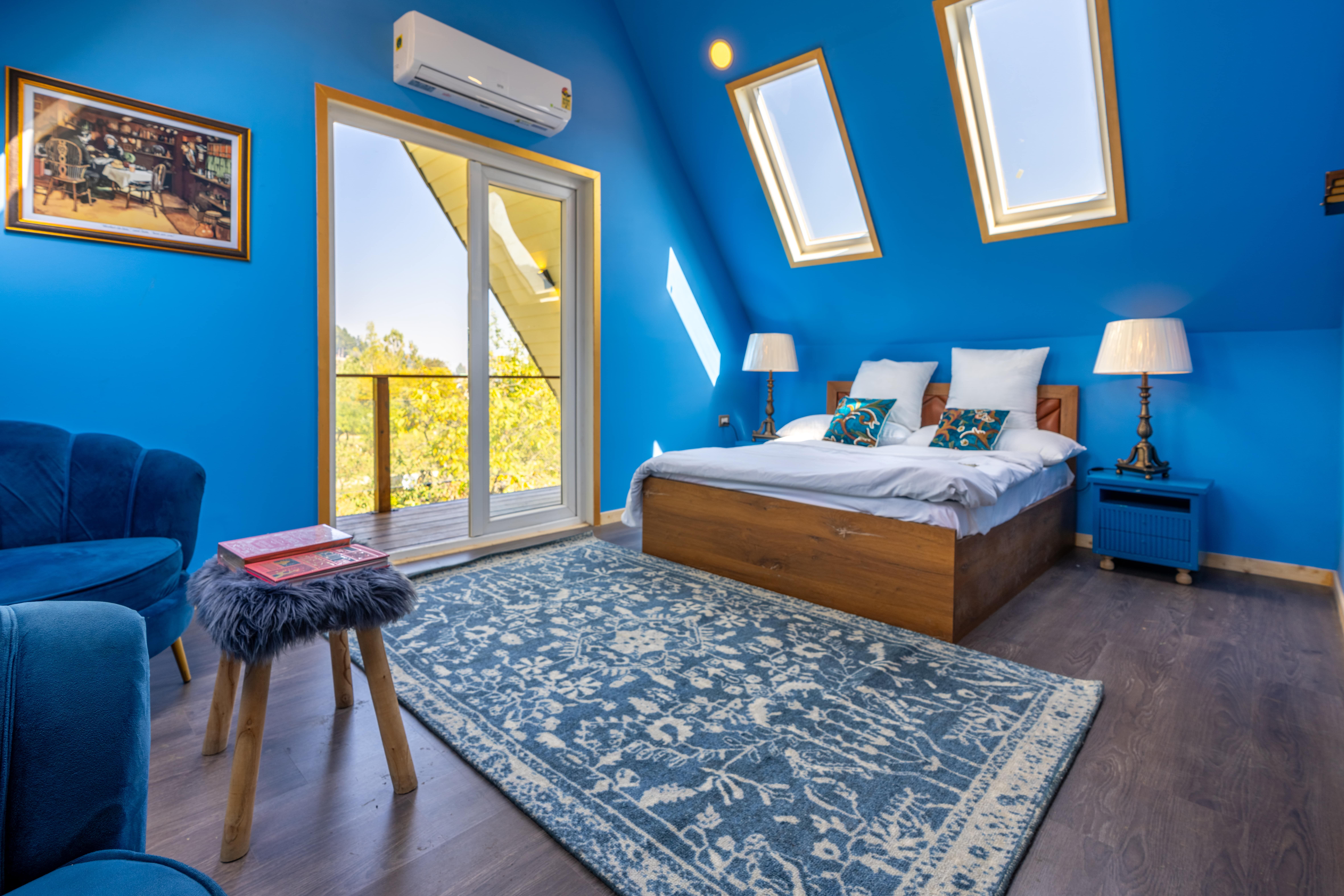 Chambre mansardée lumineuse avec murs bleus, décoration élégante et lumière naturelle grâce à des puits de lumière.