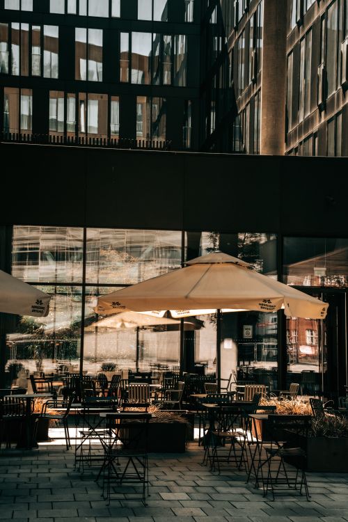 Free An inviting outdoor cafe in an urban area with umbrellas and seating arrangements. Stock Photo