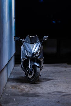 A sleek motorcycle parked in an urban alley at night, featuring dramatic lighting and modern design.