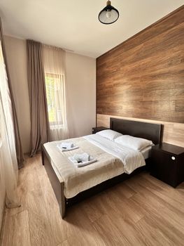 Modern bedroom with wood accents and ample natural light, creating a tranquil atmosphere.