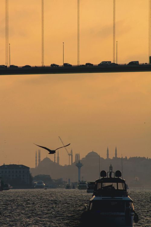 Free A captivating sunset over Istanbul's Bosphorus with a bridge, skyline, and boat. Stock Photo