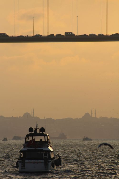 Free A striking view of the Bosphorus at sunset with boats and a busy bridge overhead. Stock Photo