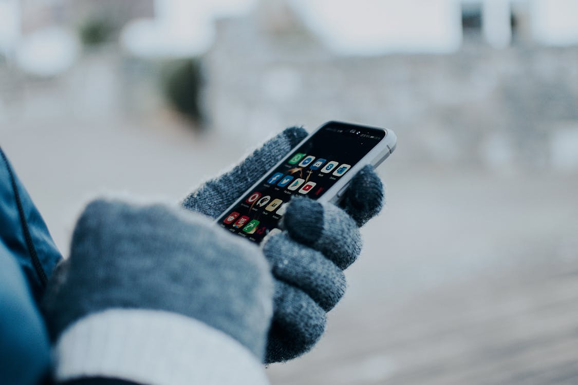 Free Person Wearing Gloves Holding a Cellphone Stock Photo
