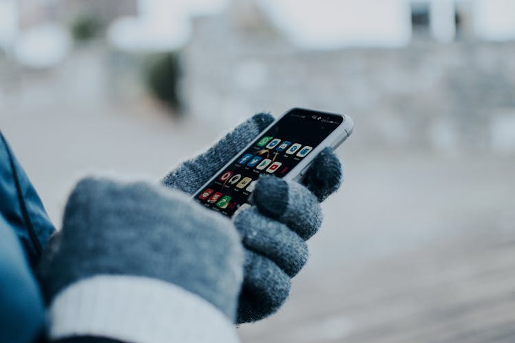 Person Wearing Gloves Holding A Cellphone