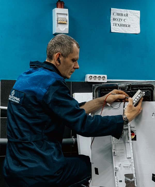 Appliance repair technician in a blue uniform fixing a home appliance