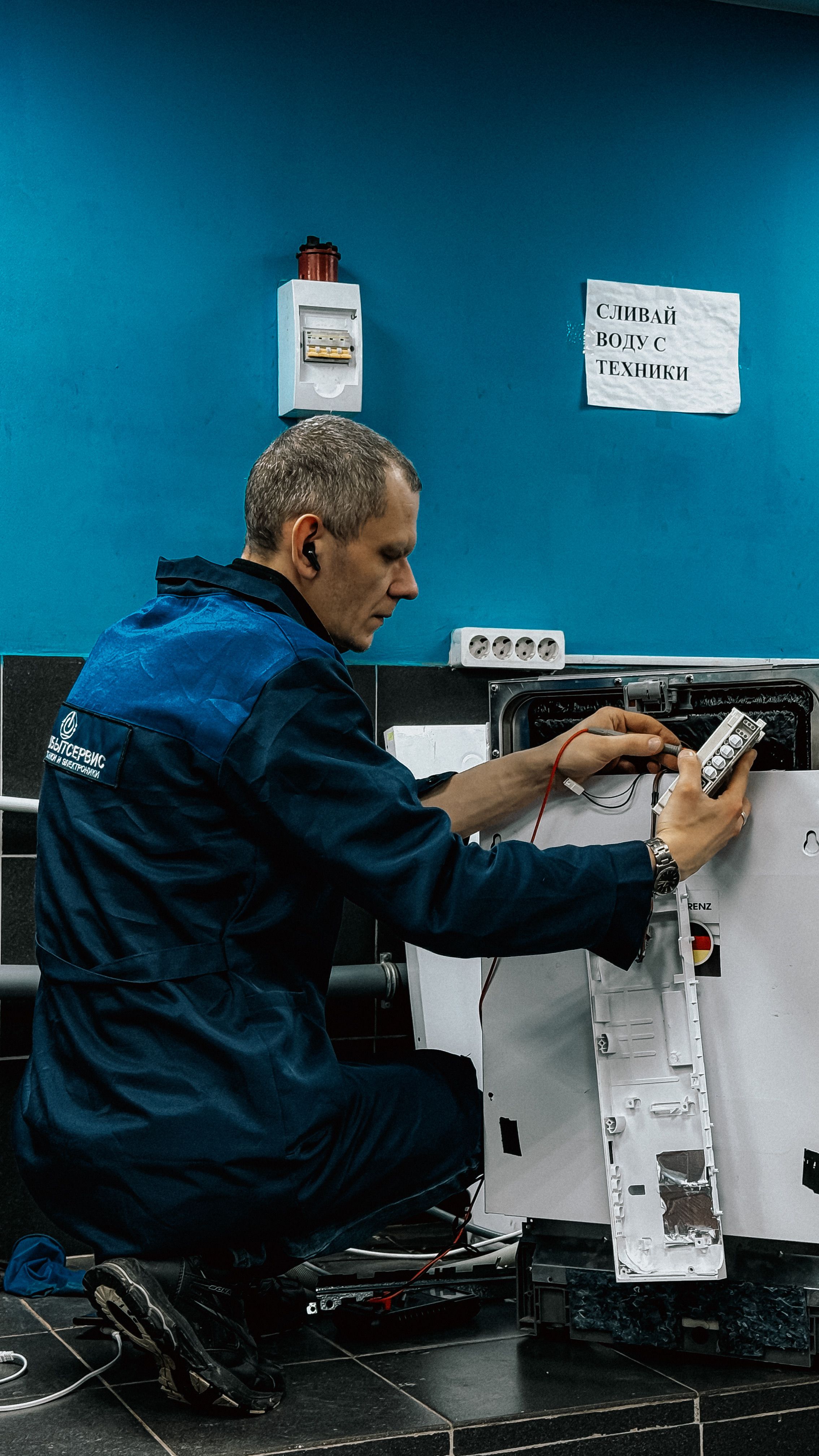 Technician in blue uniform repairing a home appliance