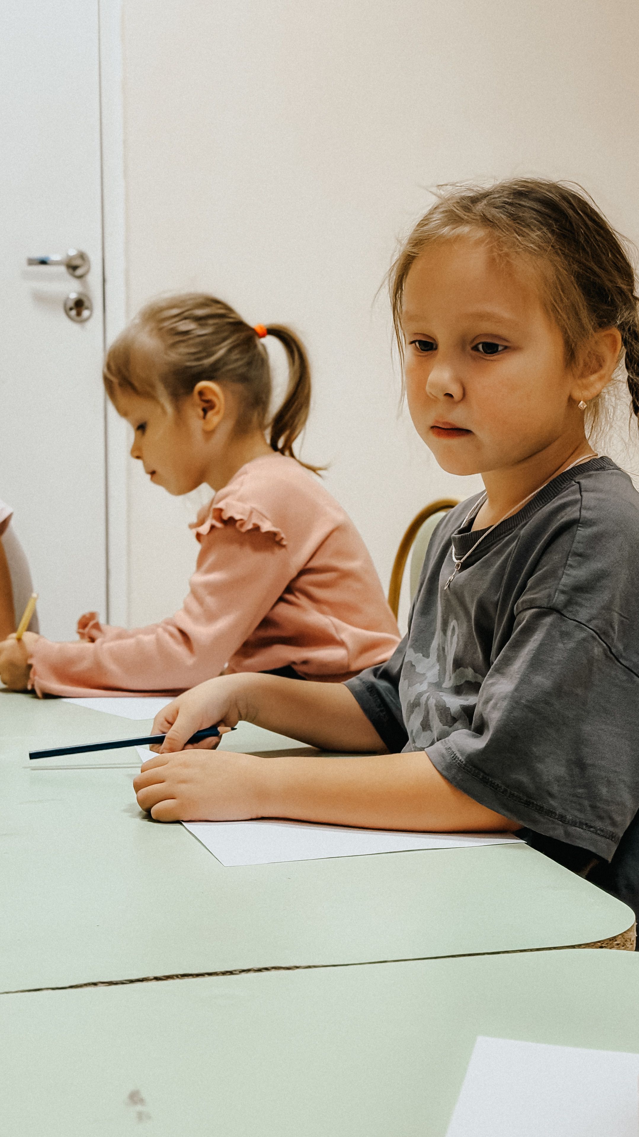 Dua anak sedang menggambar dan menulis bersama di meja