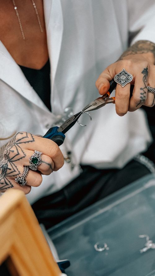 Free Close-up of tattooed hands crafting jewelry with pliers, showcasing intricate rings. Stock Photo