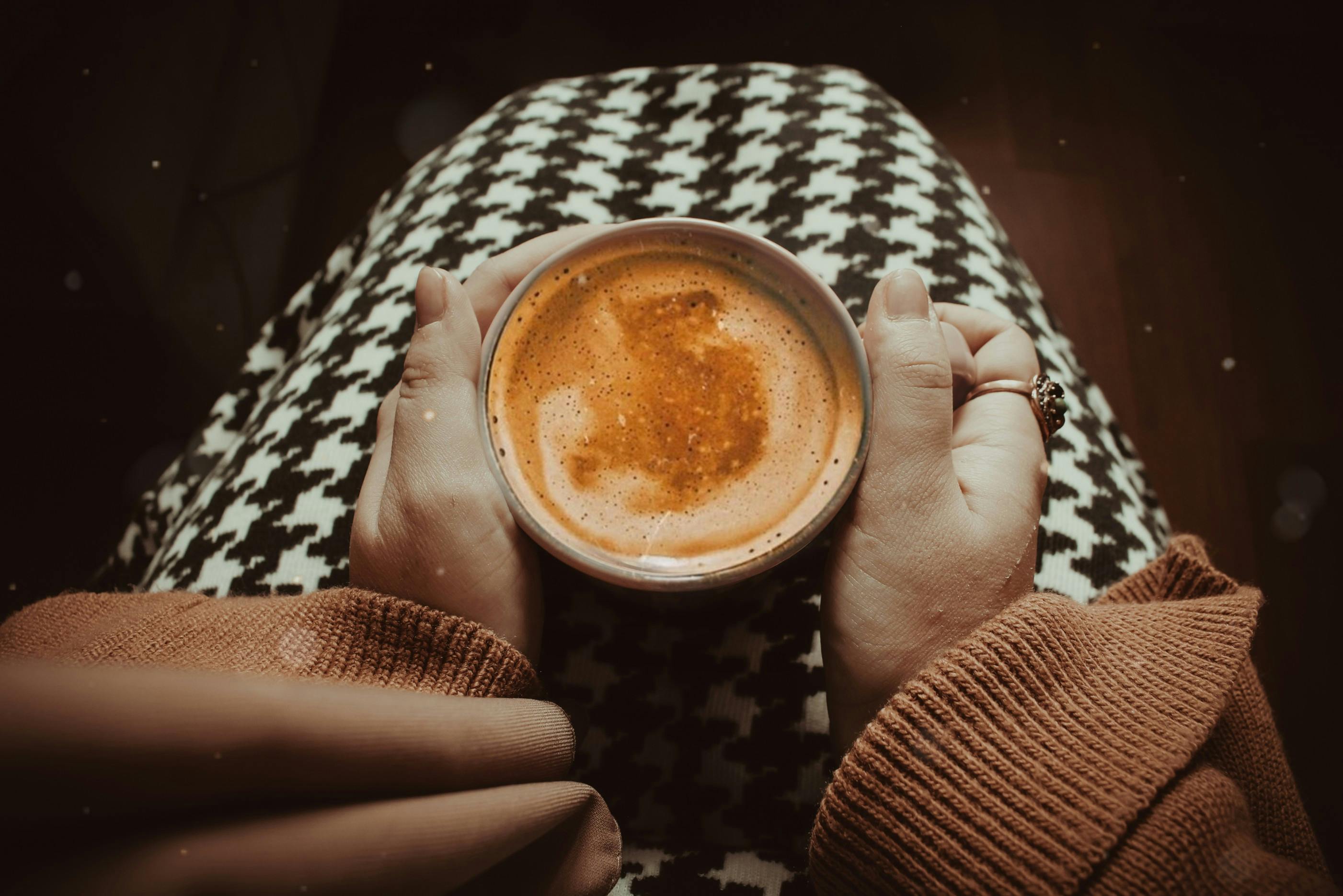Mains tenant une tasse de cappuccino chaud, moment de détente