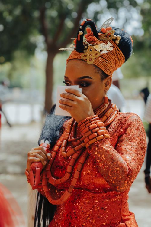 Free African woman in vibrant traditional attire enjoying a drink outdoors, showcasing cultural heritage. Stock Photo