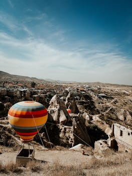 Vibrant hot air balloon hovering over Cappadocia's unique rocky terrain.