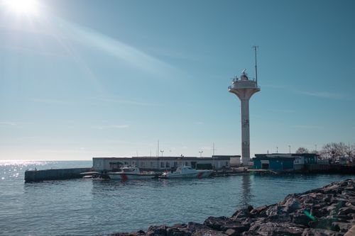 Free Bright sunny view of a lighthouse and boats at a harbor in İstanbul, capturing serene maritime atmosphere. Stock Photo